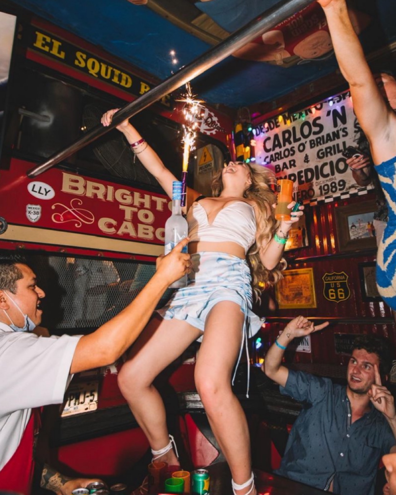 Reveler dancing on the bar at El Squid Roe holding a sparkler during Spring Break Cabo